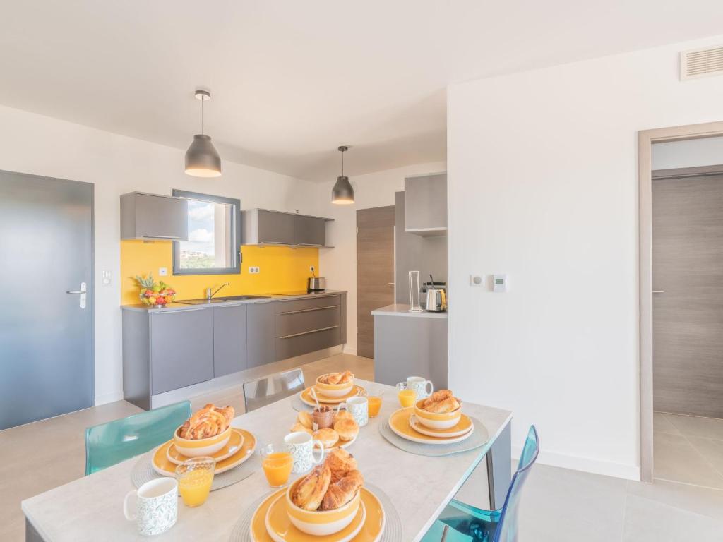 une cuisine avec une table et des assiettes de nourriture dans l'établissement Apartment Stanatura-4 by Interhome, à Porto-Vecchio