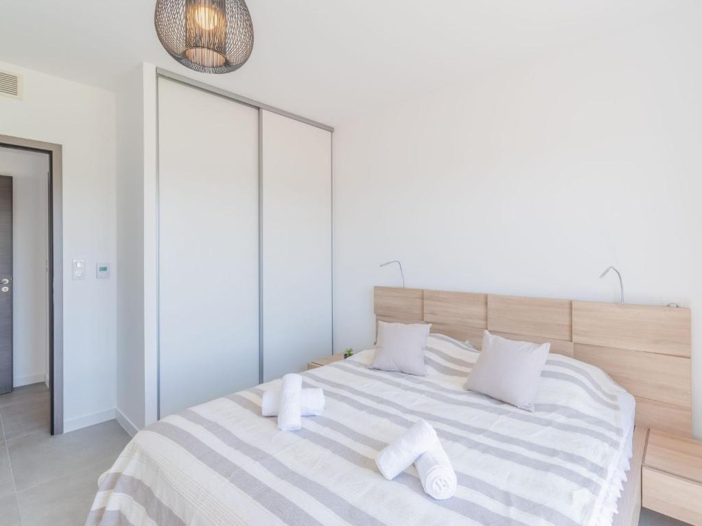 a white bedroom with a large bed with towels on it at Apartment Stanatura-4 by Interhome in Porto-Vecchio