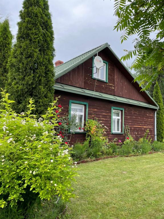 czerwony dom z oknem i kwiatami na dziedzińcu w obiekcie Dom na skraju Puszczy Białowieskiej w mieście Narewka