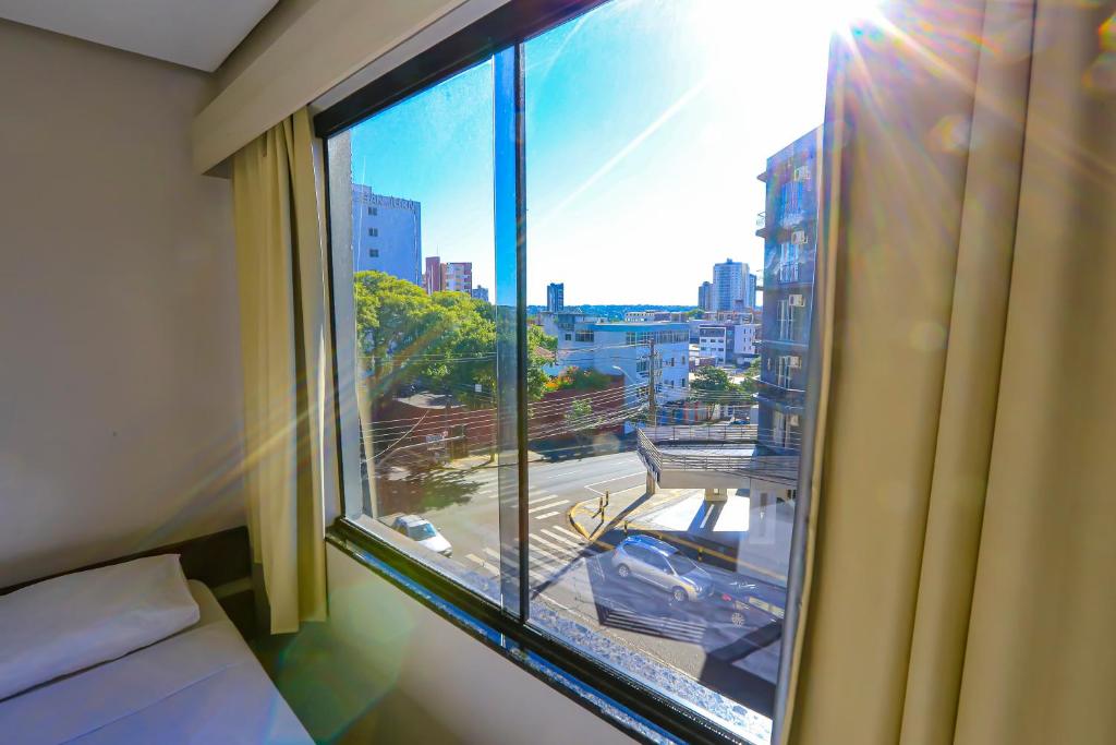 a bedroom with a window with a view of a city at Foz Express Hotel Centro in Foz do Iguaçu