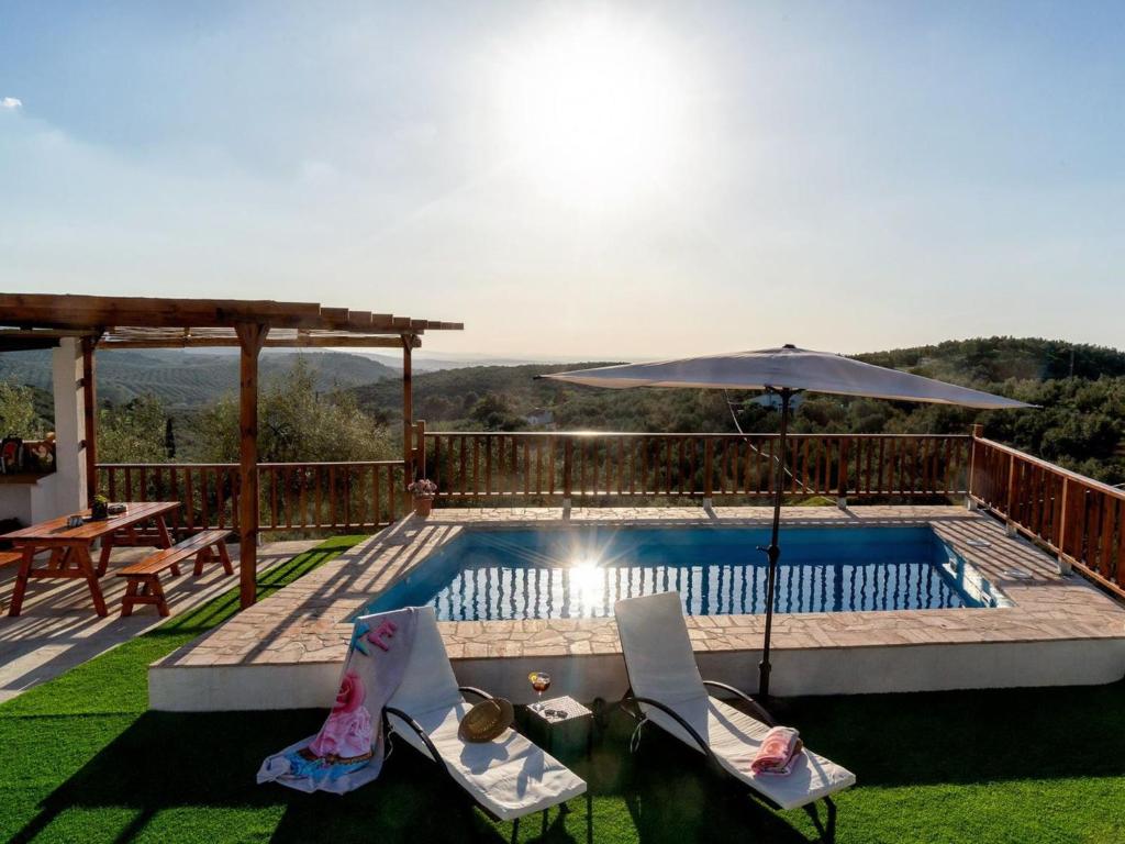 - une piscine avec 2 chaises et un parasol dans l'établissement Holiday Home La Pedriza by Interhome, à Zambra