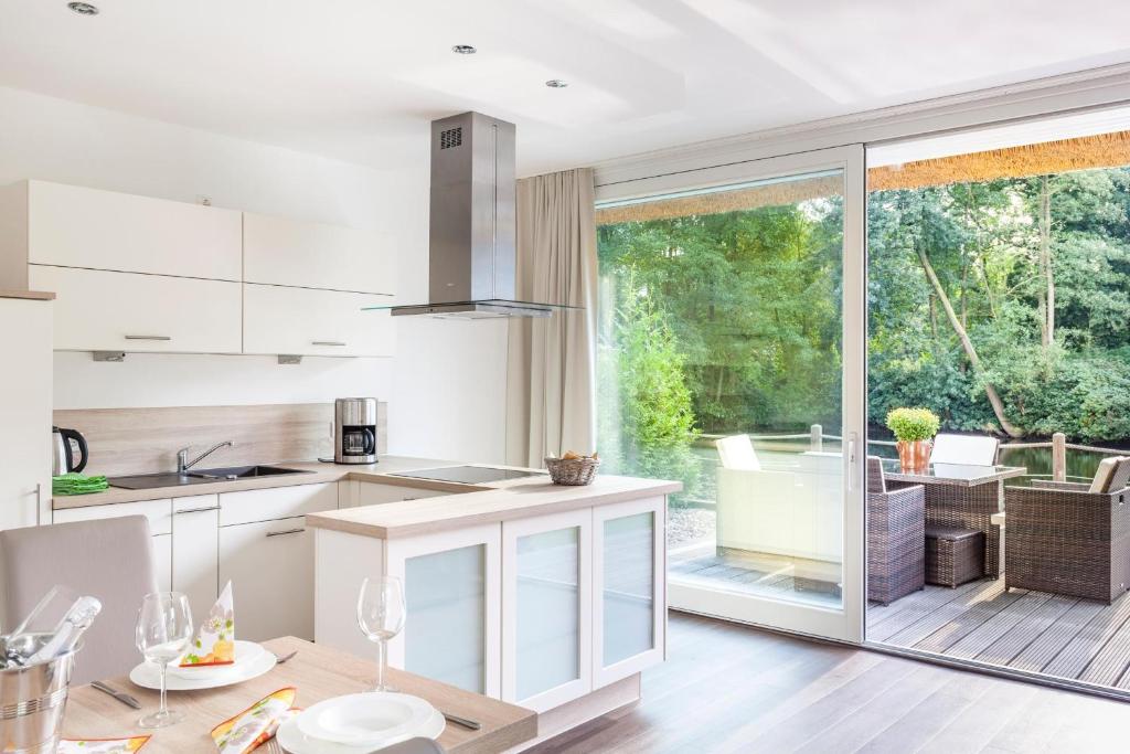 a kitchen with white cabinets and a large sliding glass door at Residenz - Sonnenglut - Seeterrasse - Sauna - Parkplatz in Bad Zwischenahn