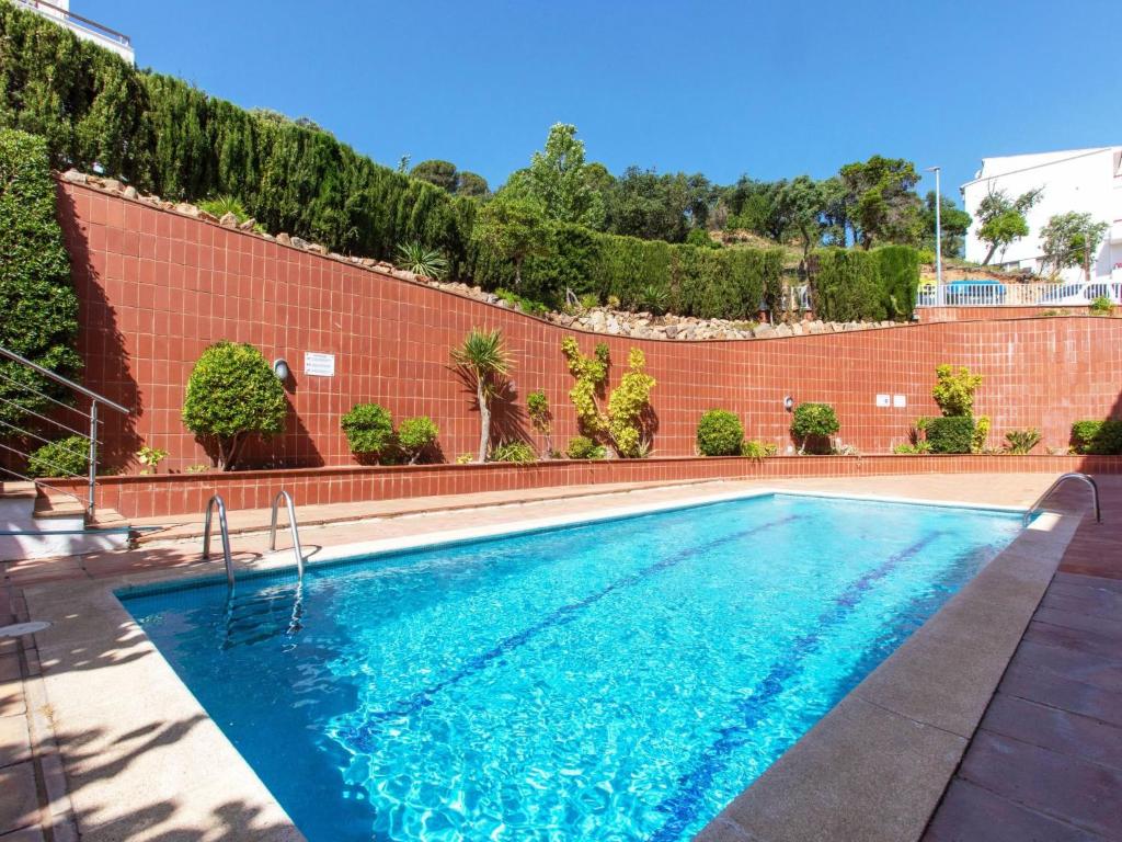 a swimming pool in front of a brick wall at Apartment Cala del mar by Interhome in Tossa de Mar