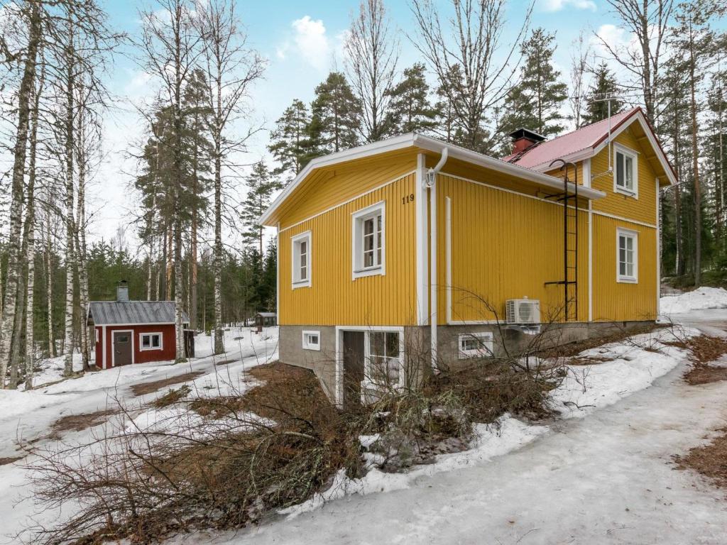 una pequeña casa amarilla en la nieve con árboles en Holiday Home Hiljanrinne by Interhome, en Haminankylä