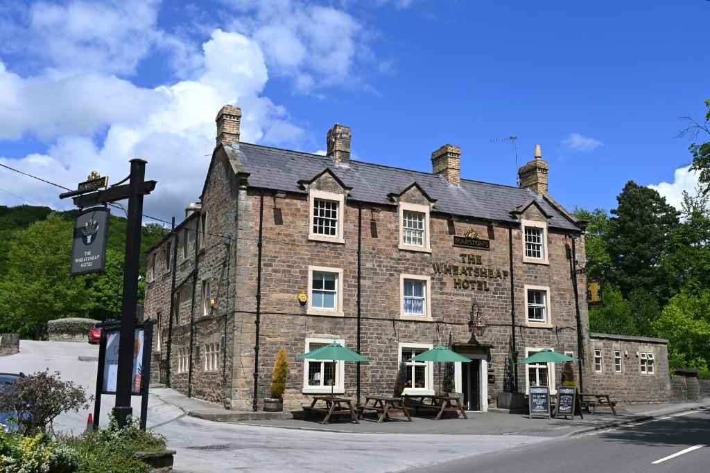 an old brick building with tables in front of it at Wheatsheaf, Baslow by Marston's Inns in Baslow