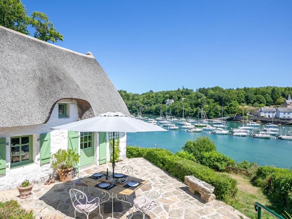 eine Terrasse mit Sonnenschirm und Booten im Wasser in der Unterkunft Holiday Home La Chaumière by Interhome in Névez