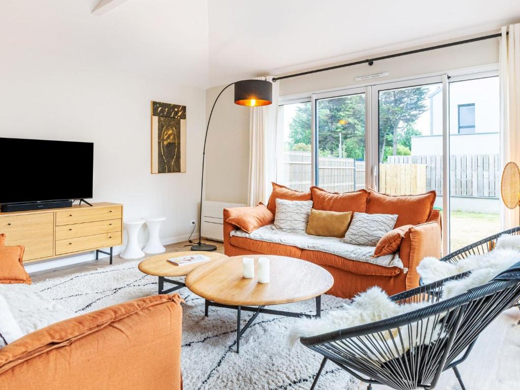 ein Wohnzimmer mit orangefarbenen Möbeln und einem Flachbild-TV in der Unterkunft Holiday Home Maison les Dunes by Interhome in Saint-Lunaire