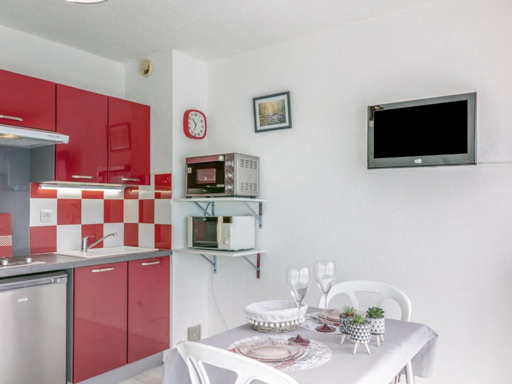 kuchnia z czerwonymi szafkami i stołem z krzesłami w obiekcie Apartment Port Plage 2 by Interhome w mieście Le Barcarès