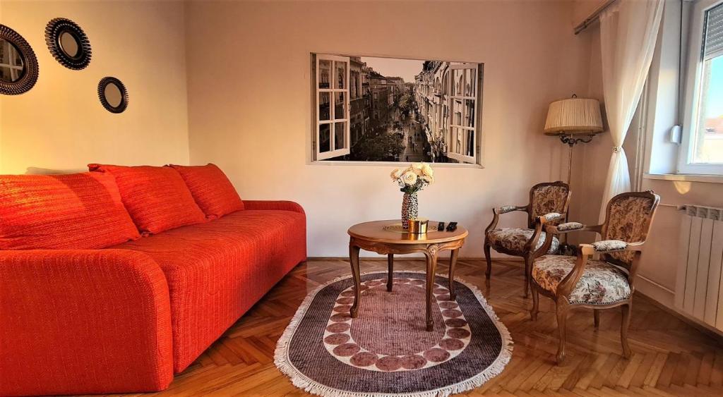 ein Wohnzimmer mit einem roten Sofa und einem Tisch in der Unterkunft Windows City Apartment in Belgrad