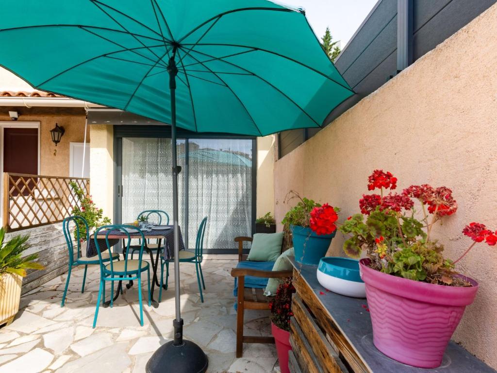 un patio avec une table et un parasol vert dans l'établissement Apartment l'orée de boulouris by Interhome, à Saint-Raphaël