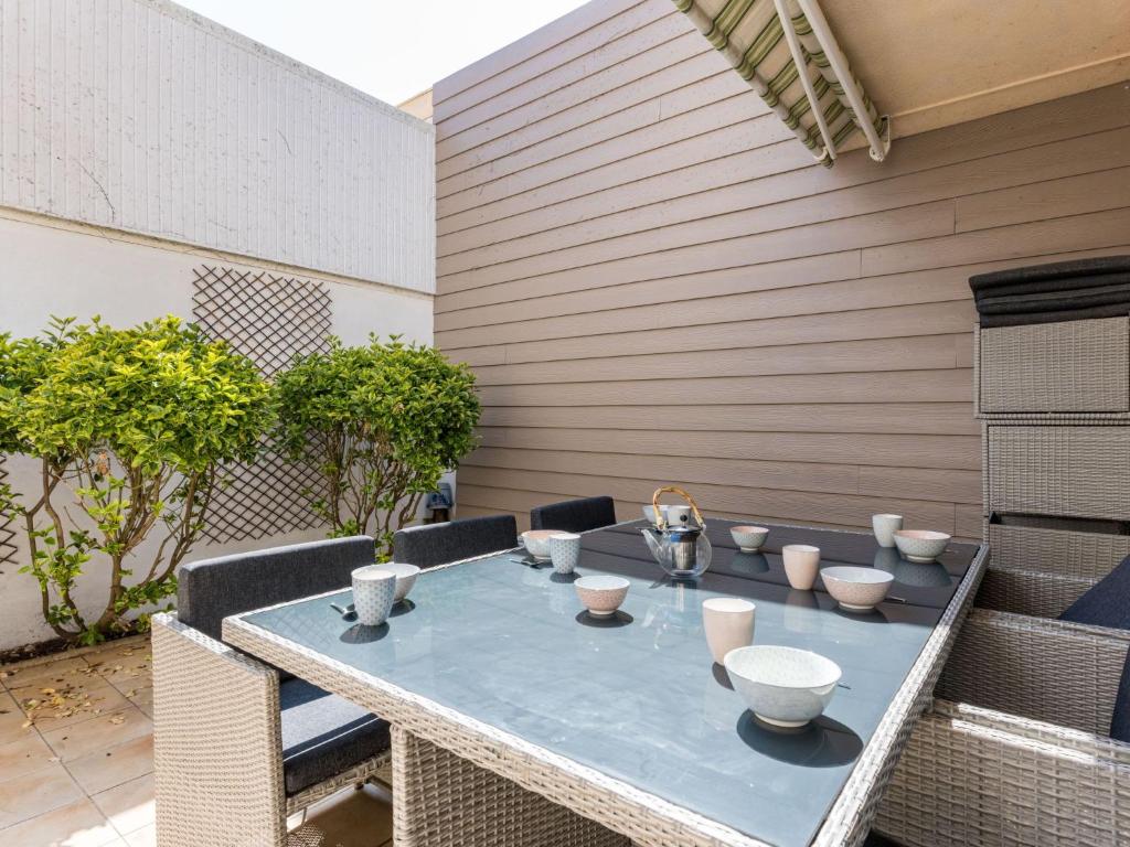 - une table avec des bols et des tasses sur la terrasse dans l'établissement Holiday Home La Petite Sourdis by Interhome, à Arcachon