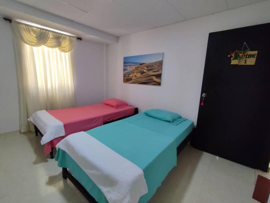 2 Betten in einem Zimmer mit Fenster in der Unterkunft Alojamiento entero, casa amplia, patio, aire in Ríohacha