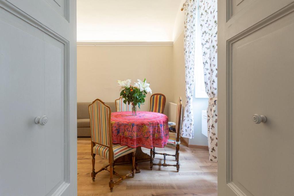 a table with chairs and a vase of flowers on it at Apartment Vespucci- quite Historic Palace in Florence