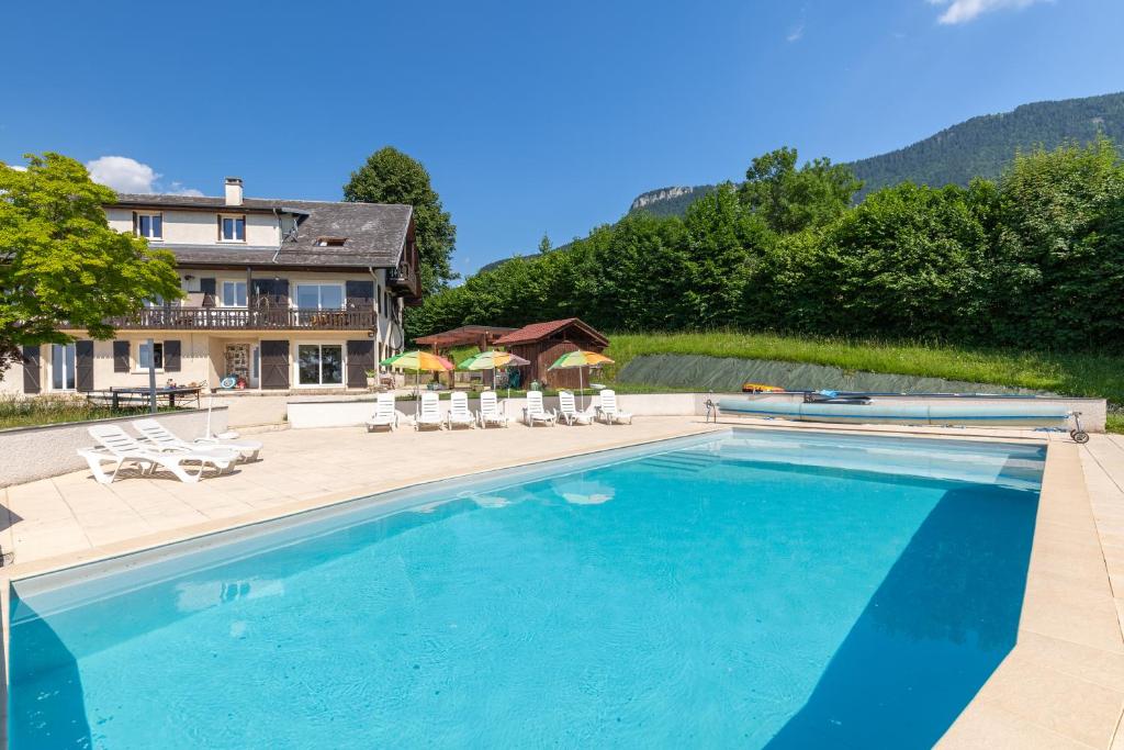 a large swimming pool with chairs and a house at Appartement Pointe de la Sambuy in Trévignin