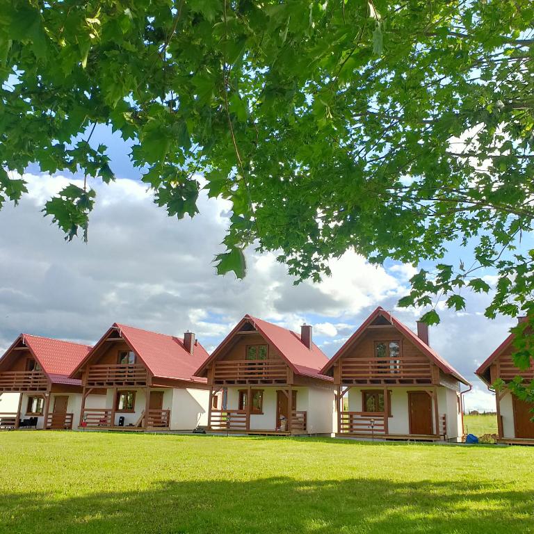 a row of houses with red roofs under a tree at KALINOWY SAD DOMKI z JACUZZI i SAUNĄ in Mikołajki