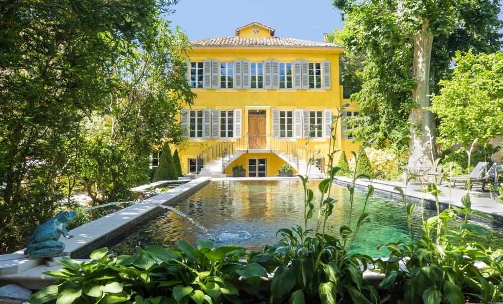 a yellow building with a pond in front of it at Villa Amara in Aix-en-Provence