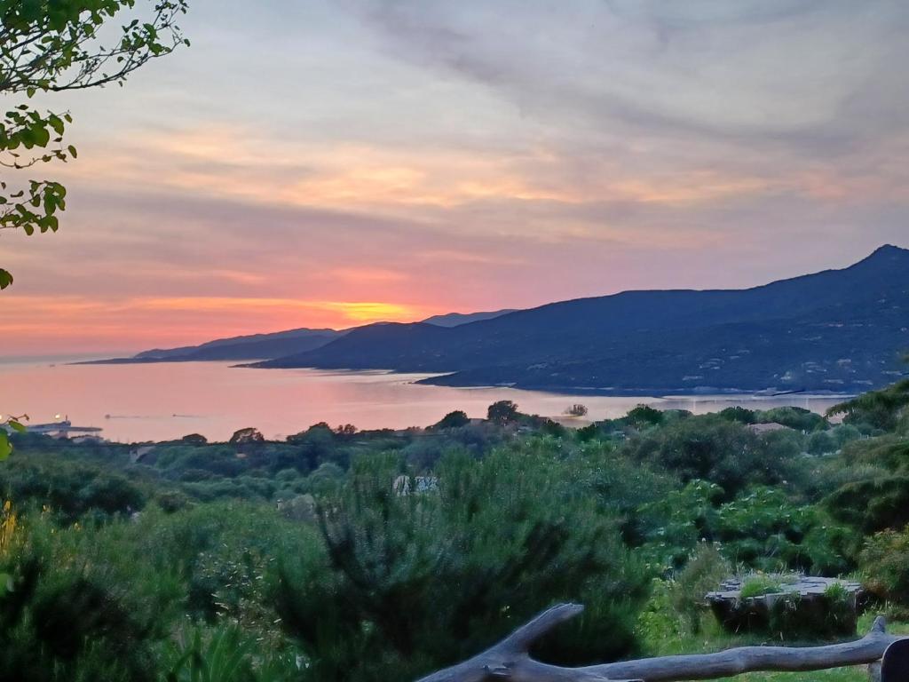 una puesta de sol sobre un cuerpo de agua con montañas en U Castellu Chambres d'hôtes & Location villa et appartements vue mer en Propriano