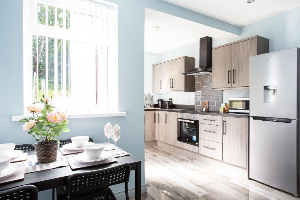 a kitchen with a table and a white refrigerator at Fully refurbished North Belfast Home 3 in Belfast