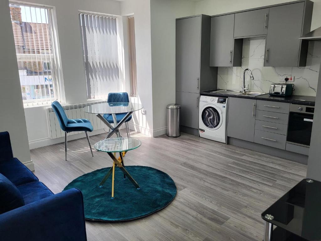 ein Wohnzimmer mit einem Tisch und einer Küche in der Unterkunft 1 Bed Flat, Fibre Broadband, New, Washer Dryer, 10 mins from city centre in Dartford