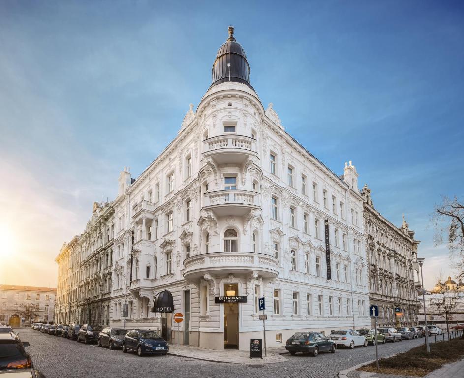 un grande edificio bianco su una strada con auto parcheggiate di Theresian Hotel a Olomouc