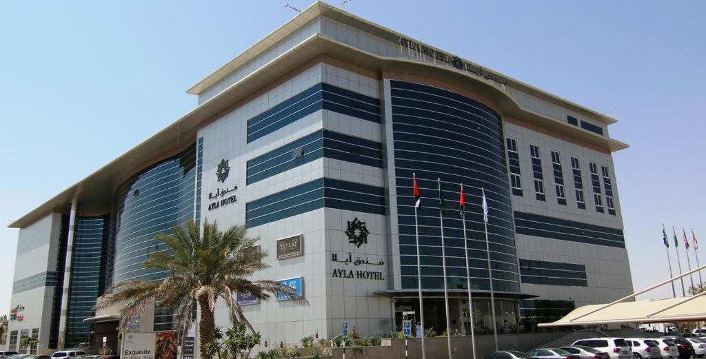 a large building with a palm tree in front of it at Ayla Hotel in Al Ain