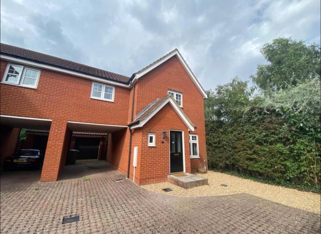 a red brick house with a large driveway at Modern + Secluded 3 bed, 10 mins into city centre in Spixworth