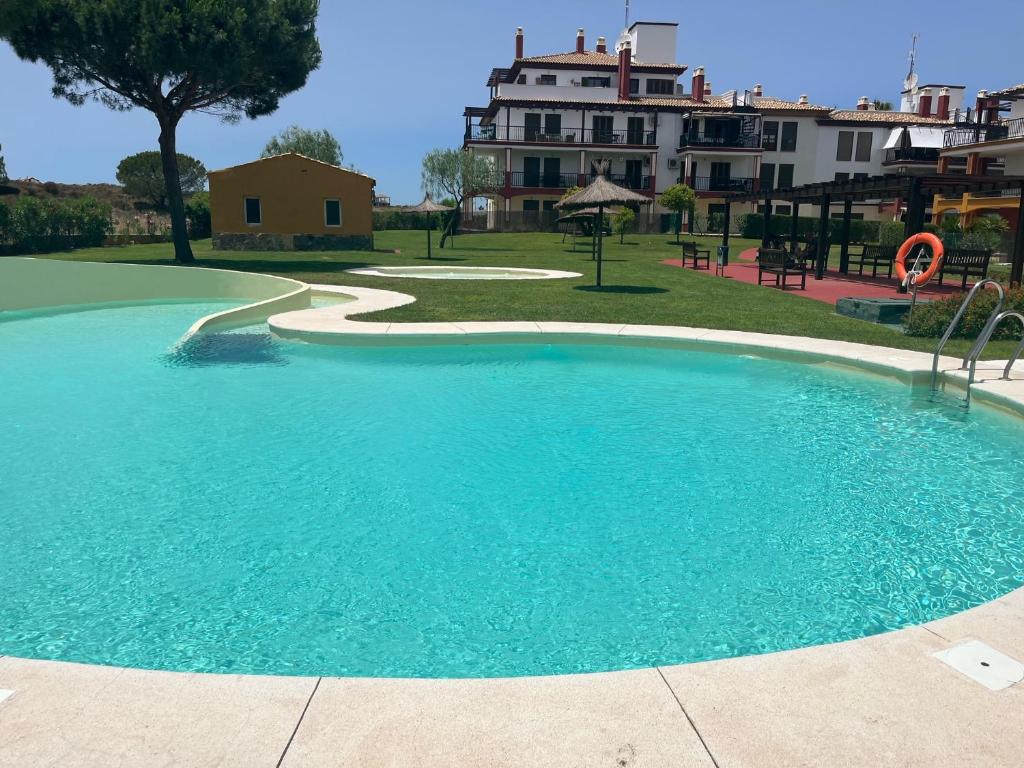 duży niebieski basen z budynkiem w tle w obiekcie Ayamonte - Vista Esuri Golf and Beach w mieście Huelva