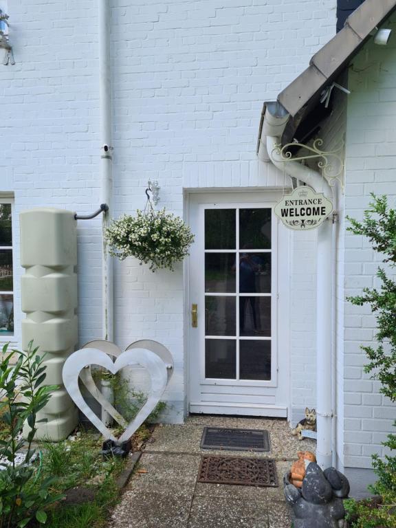 a white house with two heart sculptures in front of the door at Das Weisse Haus Bockholt in Soltendieck