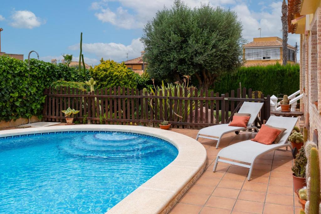 a swimming pool with two chairs next to a fence at Fidalsa Coastal Soul in Torrevieja