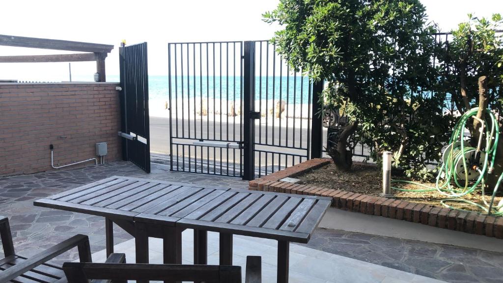 a wooden table and chairs in front of a fence at Beach Appartament in Marina di Montemarciano
