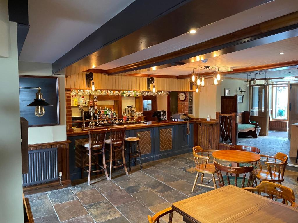 un restaurante con un bar con mesas y sillas de madera en The Swan Inn en East Ilsley