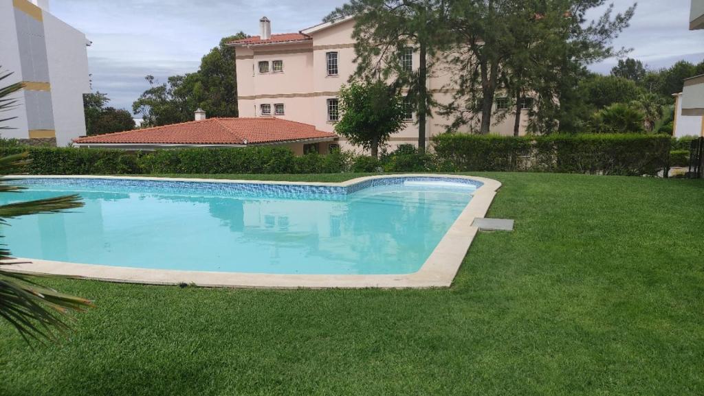 a swimming pool in the grass in front of a house at Authentic Charm Soltroia in Troia