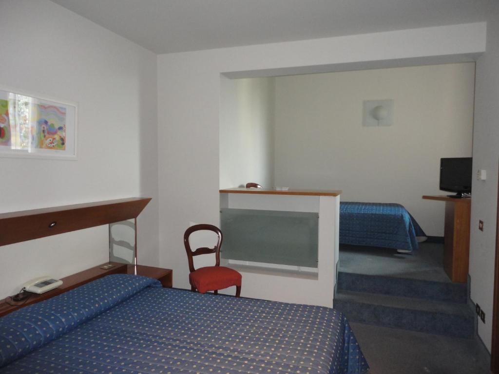 een hotelkamer met 2 bedden en een rode stoel bij Cravero Rooms in Caltignaga