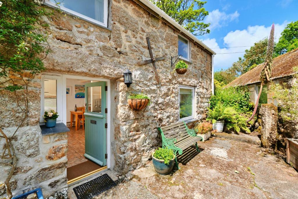 una casa de piedra con una puerta verde y un banco en Finest Retreats - Waterside Cottage en Nancledra