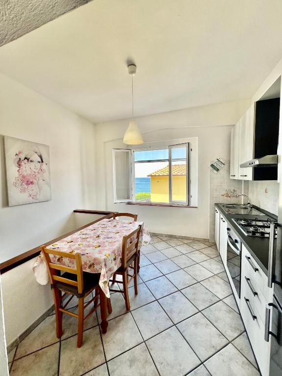 a kitchen with a table and chairs and a window at Appartamento La Baia in Fetovaia