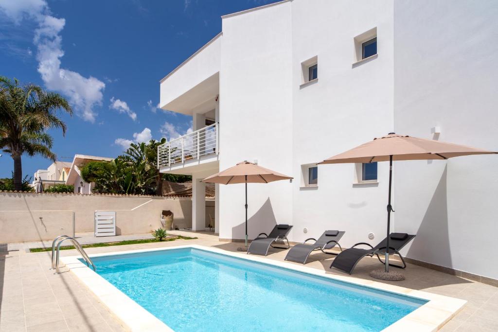 een huis met een zwembad en twee parasols bij Baia Marzamemi appartamenti Vendicari, Balata, Tonnara, Cortile del Rais in Marzamemi