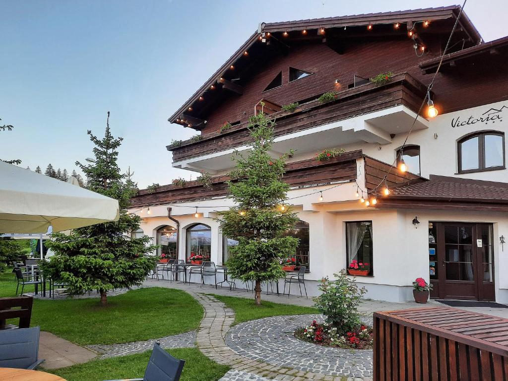 a large white building with a patio in front of it at Pensiune & Restaurant Victoria in Păltiniş