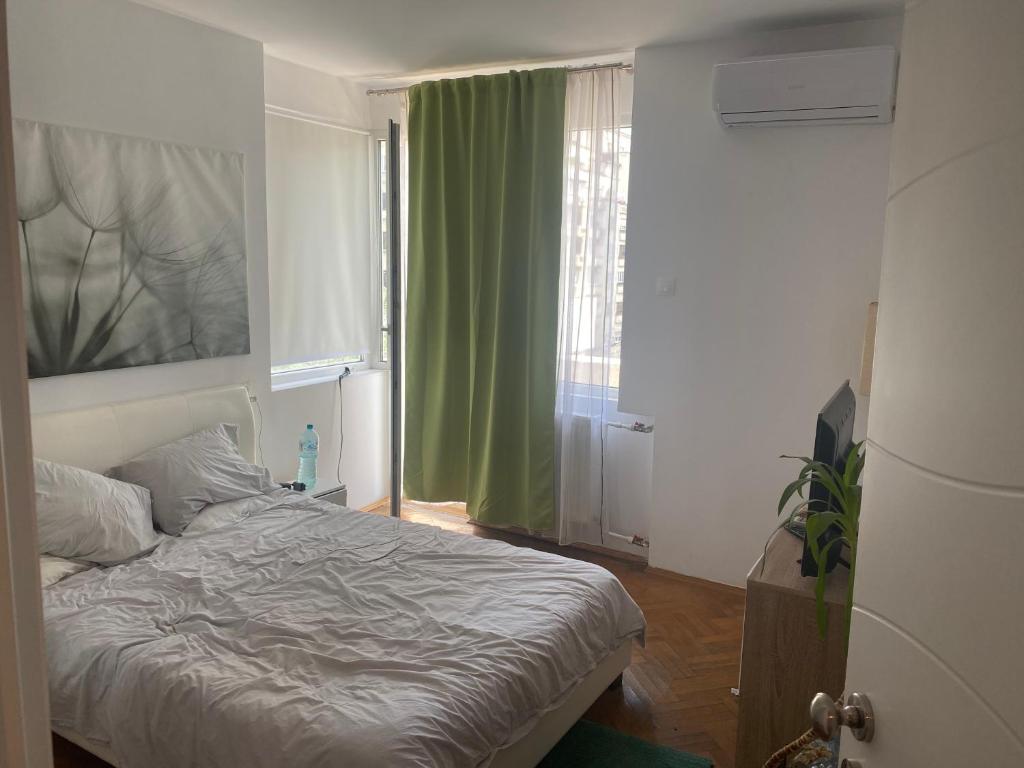 - une chambre avec un lit et une fenêtre avec des rideaux verts dans l'établissement Bucarest B&B, à Bucarest