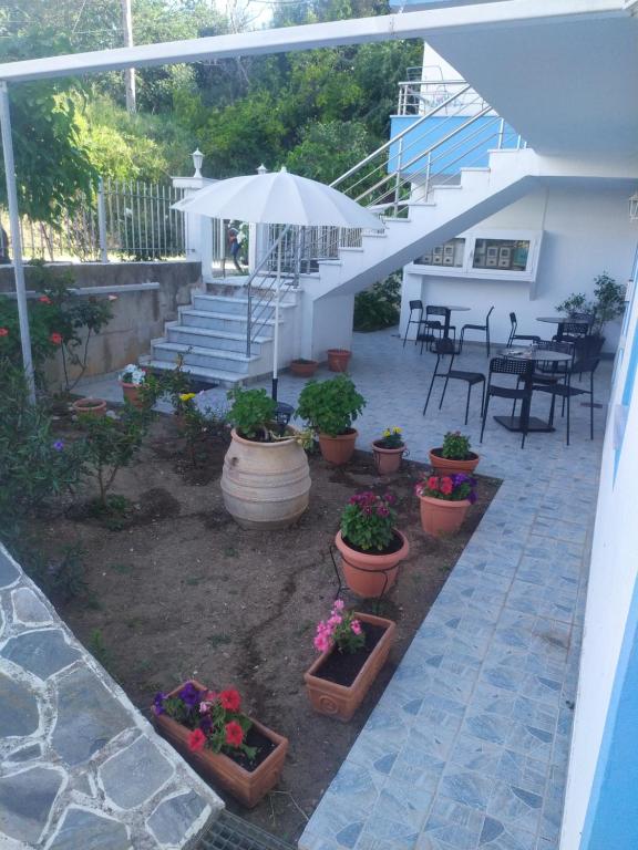 eine Terrasse mit Topfpflanzen, einem Regenschirm und einer Treppe in der Unterkunft KANALI HOLIDAYS APARTMENT 1 in Kanali