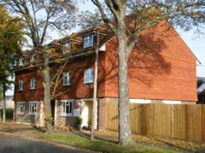 une grande maison rouge avec une clôture devant elle dans l'établissement Springfields, à Horsham