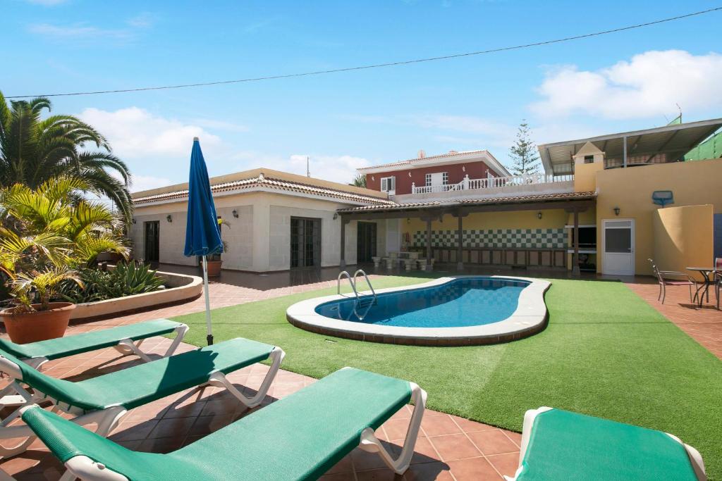 einen Hinterhof mit Pool und Stühlen und ein Haus in der Unterkunft Villa Tazana in Icod de los Vinos