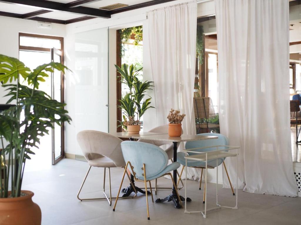 a dining room with a table and chairs and plants at Hotel As Hortensias in Corcubión