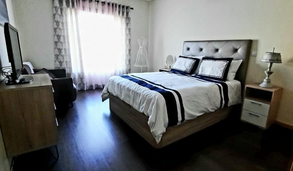 - une chambre avec un grand lit et une fenêtre dans l'établissement Lendas de Portugal, à Olhos de Água