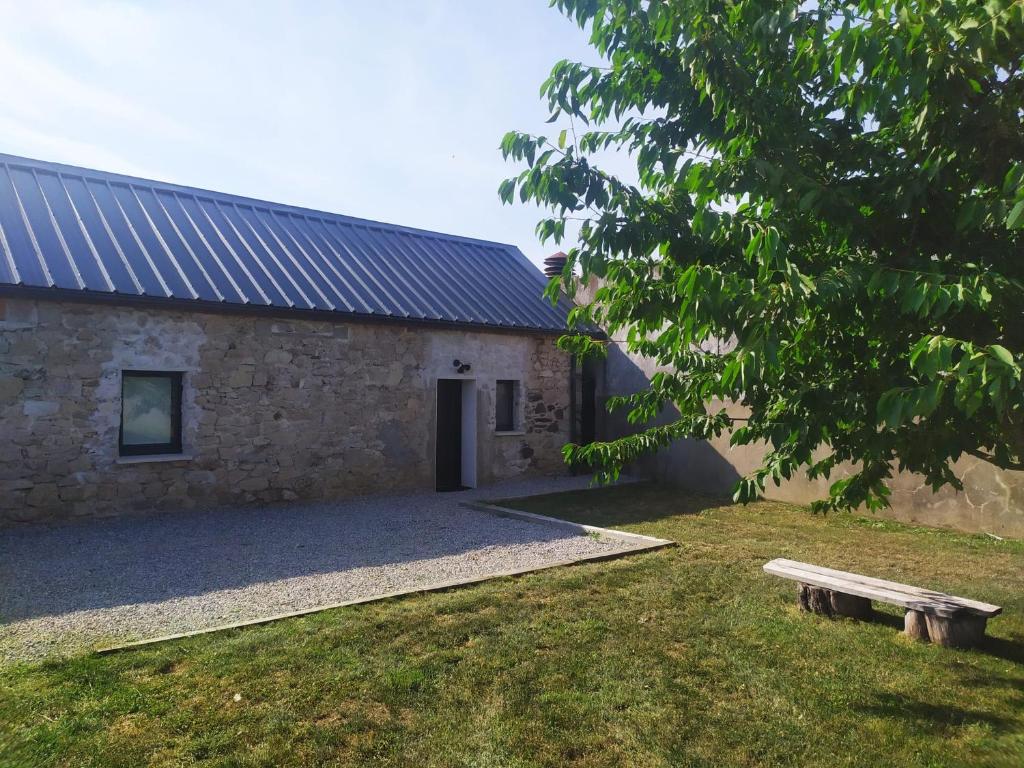 un edificio de piedra con un banco delante en Location à Argentat-sur-Dordogne en Argentat