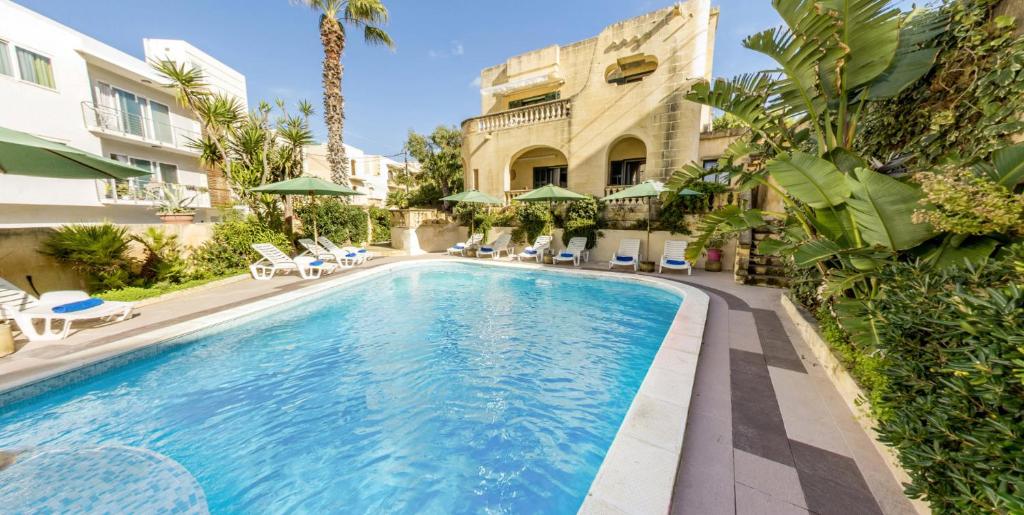 a swimming pool in front of a building at Villa Xemxija in Xlendi