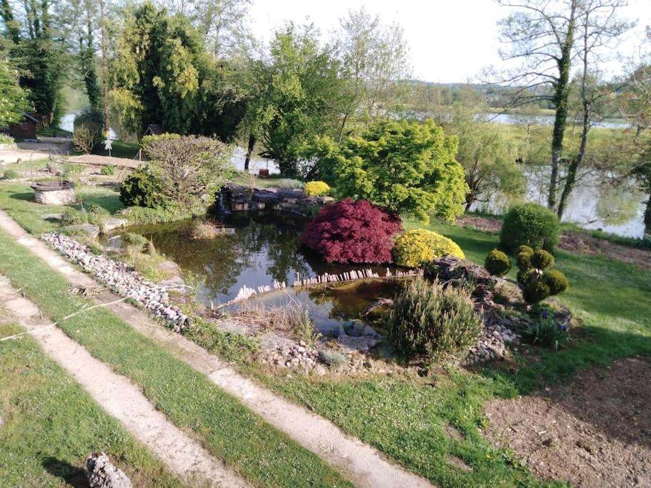 a garden with a pond and flowers and a bridge at Au petit gravelot 
