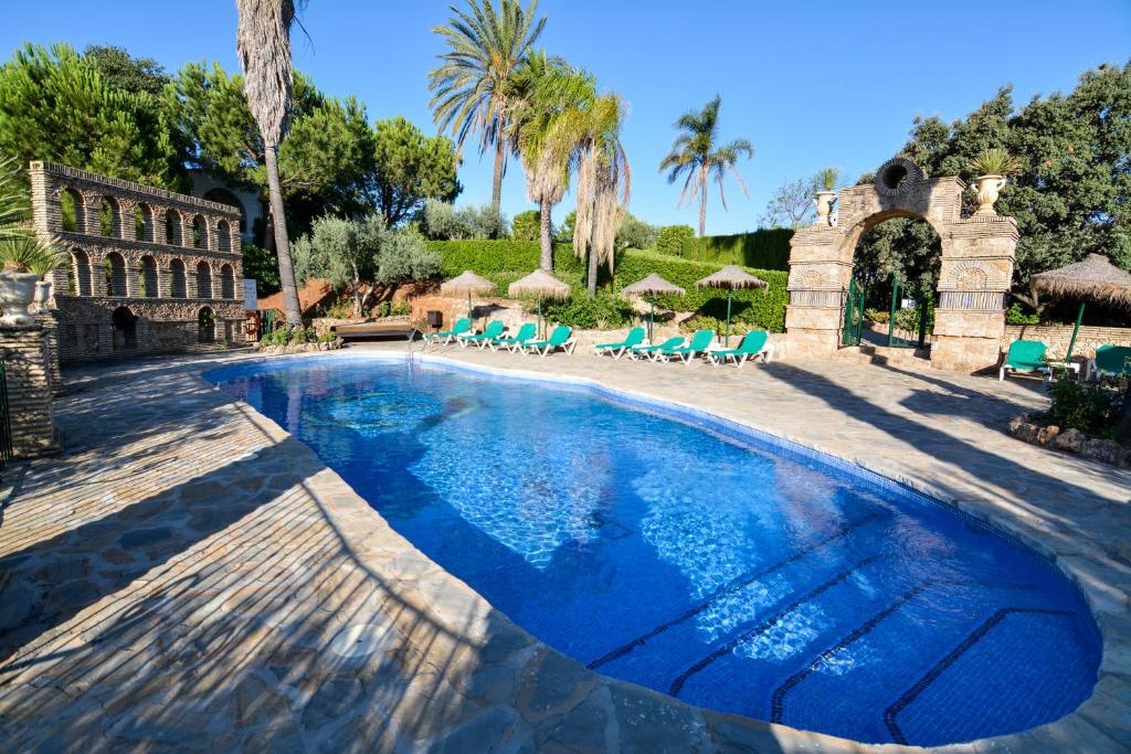 une piscine avec des chaises bleues et un bâtiment dans l'établissement Tu Villa Rural Acequia 5 Dormitorios, à Alhaurín el Grande