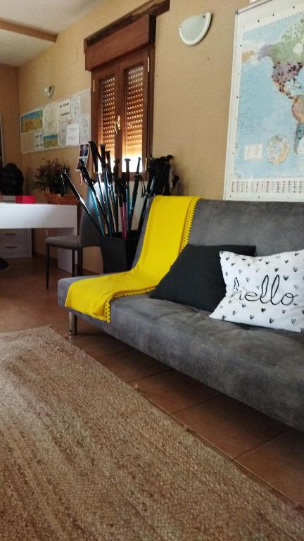 a couch with a yellow blanket on it in a living room at Albergue de peregrinos Santa Marina in Molinaseca
