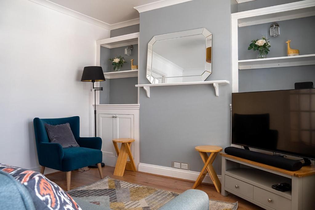 a living room with a blue chair and a mirror at cosy and peaceful near Ashford town centre in Kent