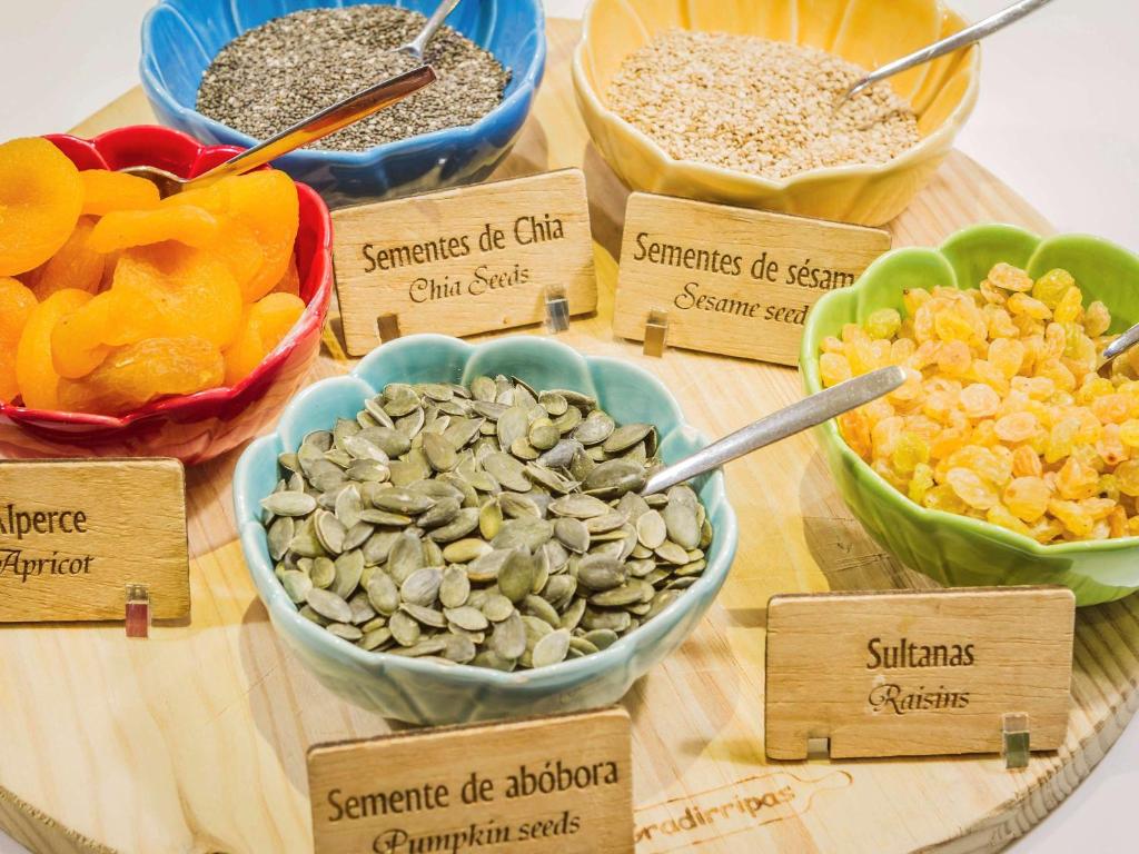 a table with bowls of different types of nuts and seeds at Hotel Ibis Lisboa Sintra in Sintra